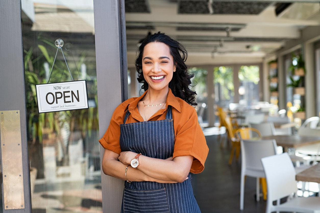 Business insurance: Portrait of happy business owner standing at restaurant entrance